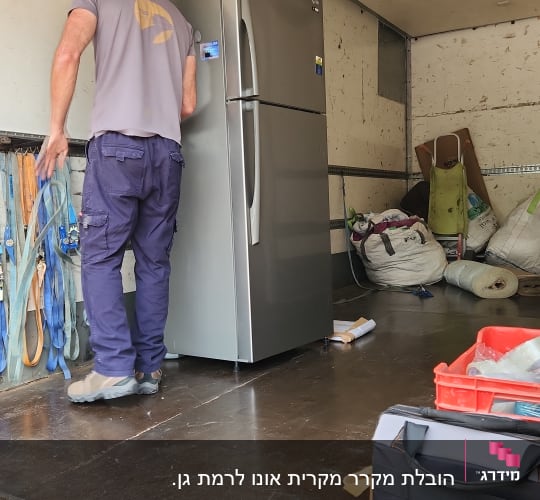 אדם מעמיס מקרר למשאית עם ציוד הובלה